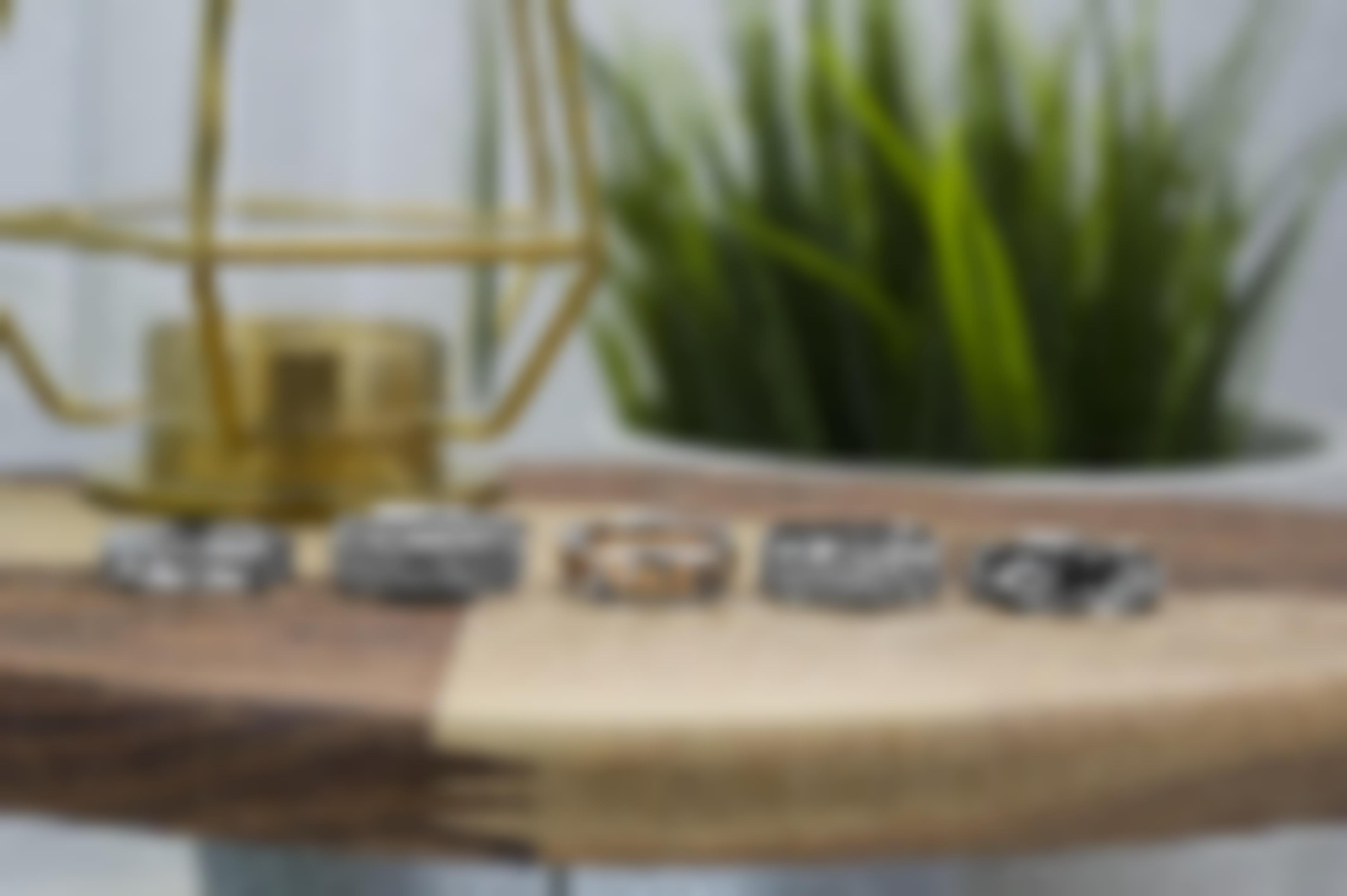 Five men’s wedding bands lined up on wooden table.