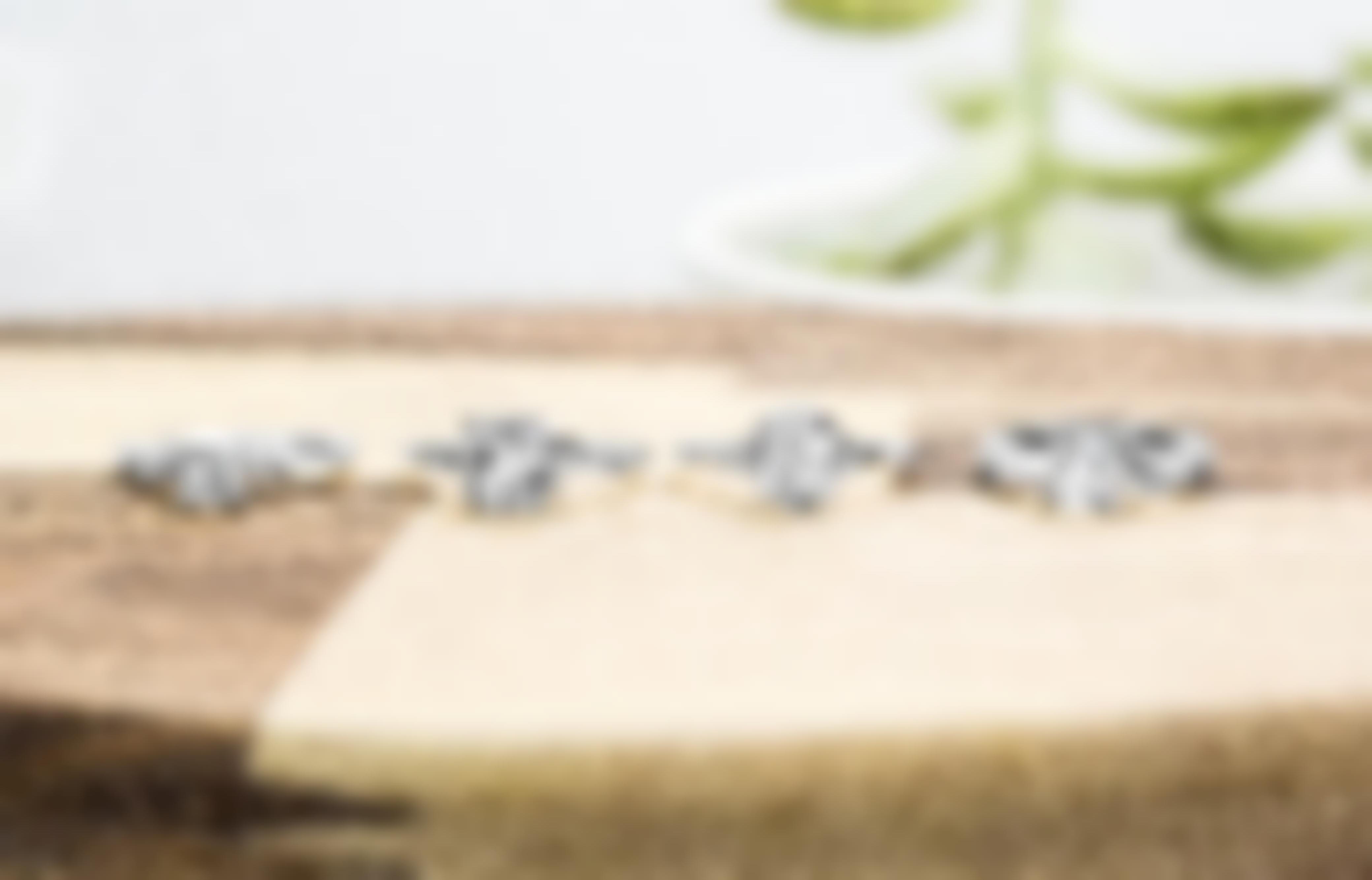 Four white gold diamond engagement rings of various shapes lined up on a wooden table.