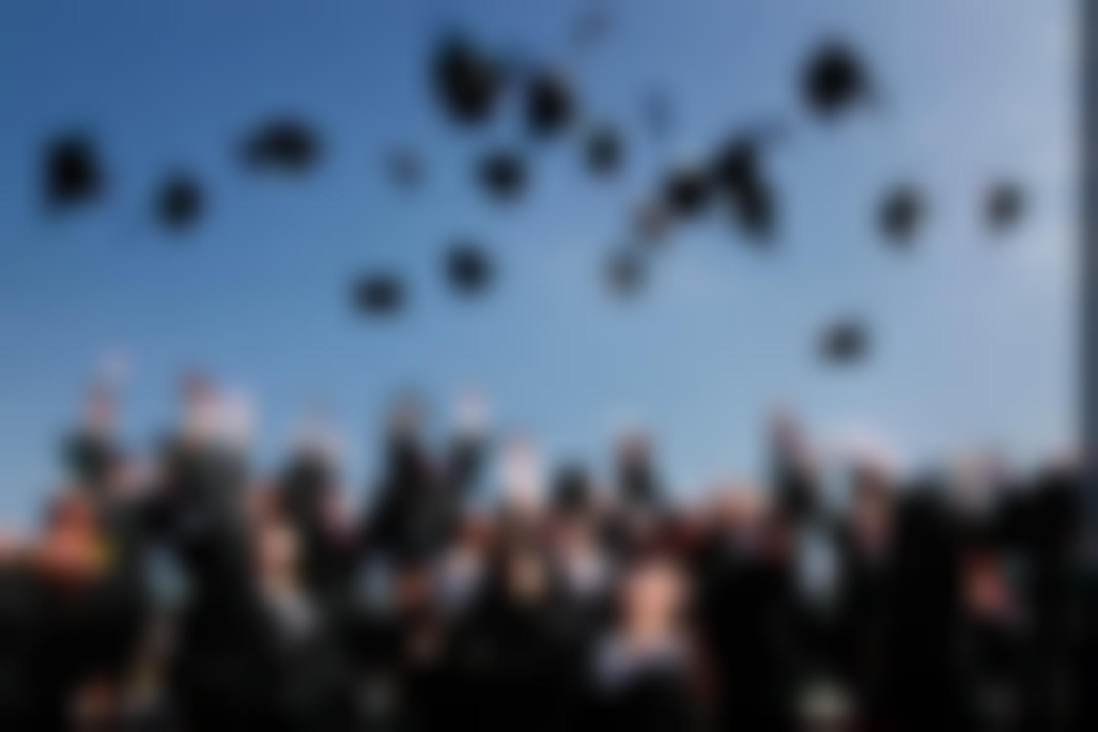 Graduates throwing caps in the air at ceremony.