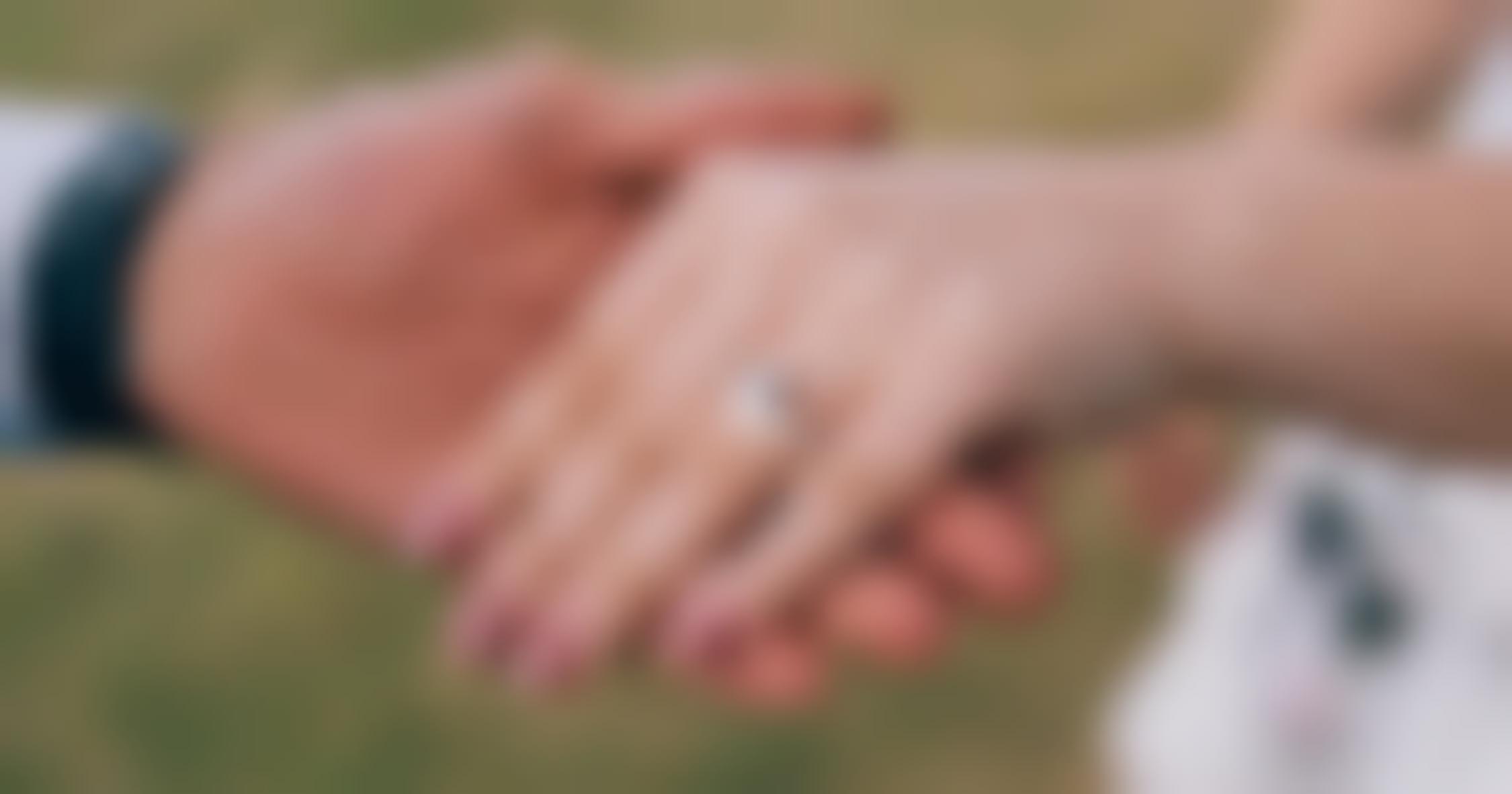 Man holding woman’s hand showing off her diamond engagement ring.