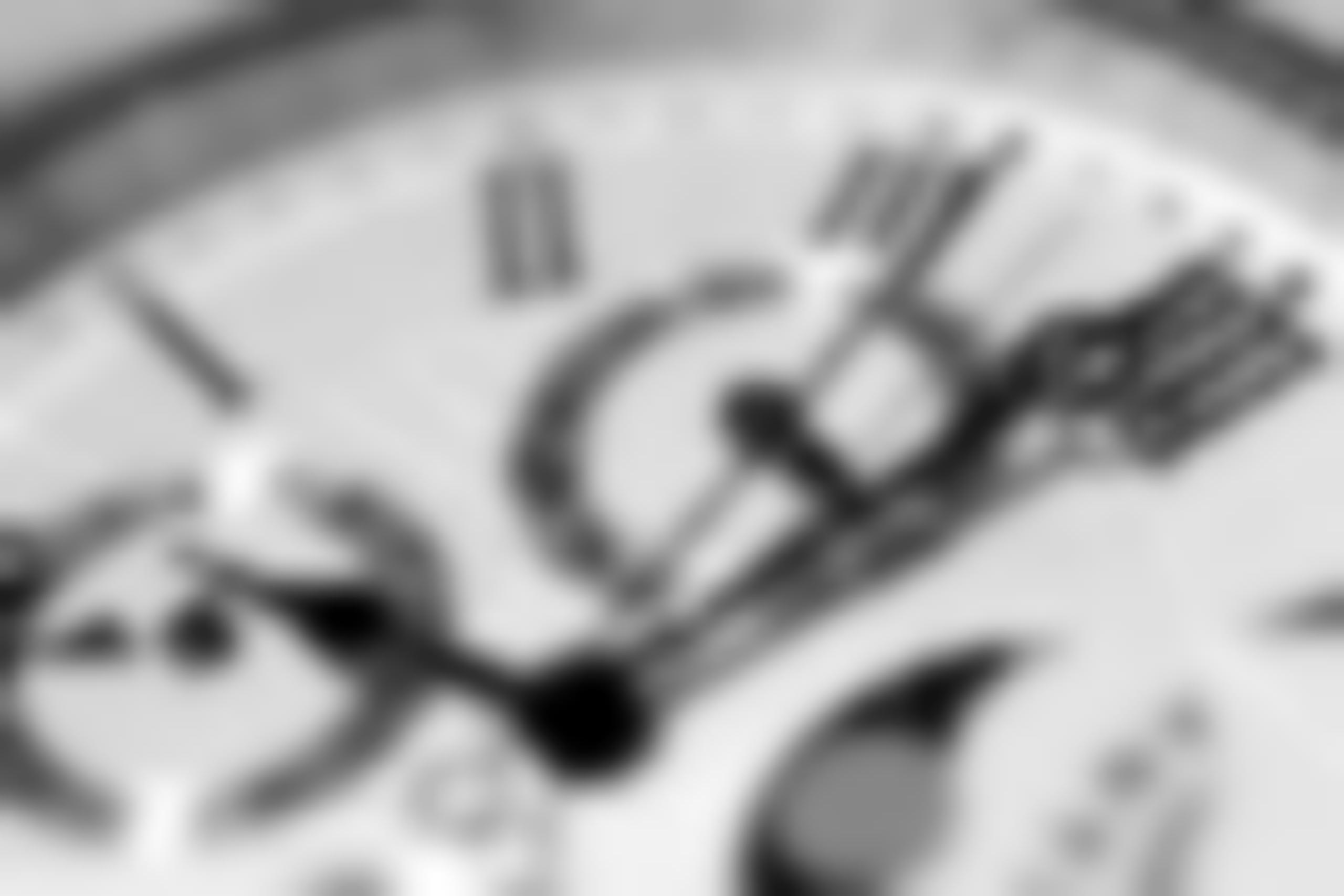 Zoomed in image of white watch dial with roman numeral markers.