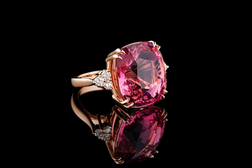 Rose gold ring centered with red tourmaline and diamond side stones.