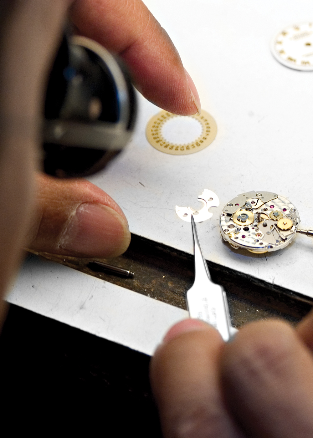 Jeweler repairing watch movement at their bench.