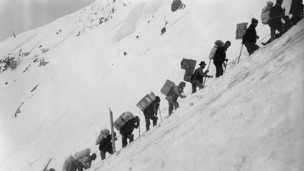 Black and white photo of men climbing trail during Klondike gold rush.