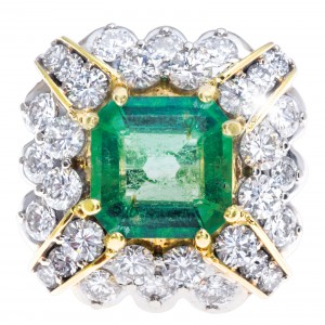 Yellow gold cocktail ring centered with an emerald surrounded by diamonds.