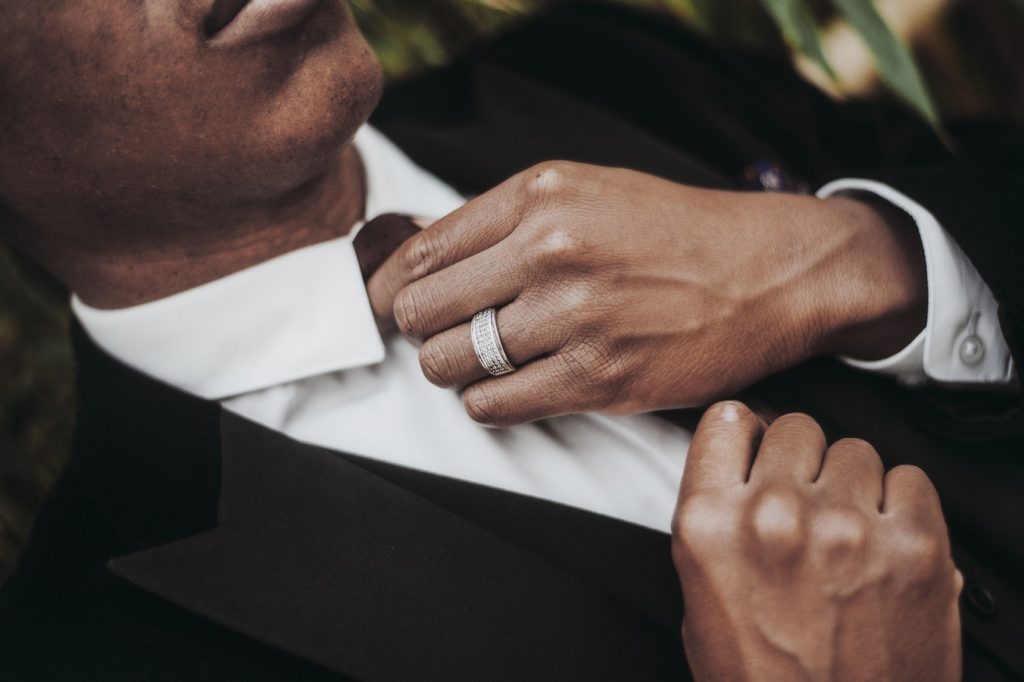 Groom’s hand featuring white gold wedding band.