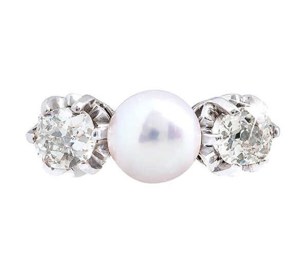 Antique platinum three-stone ring set with a white pearl and diamond side stones.