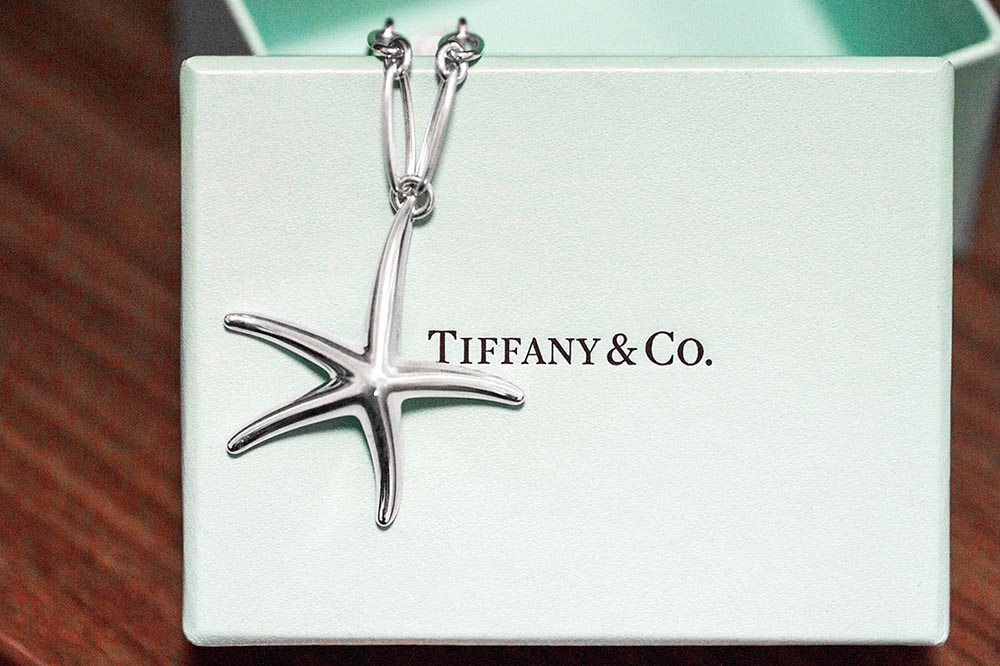 Vintage sterling silver Tiffany & Co. starfish pendant necklace on top of Tiffany box.