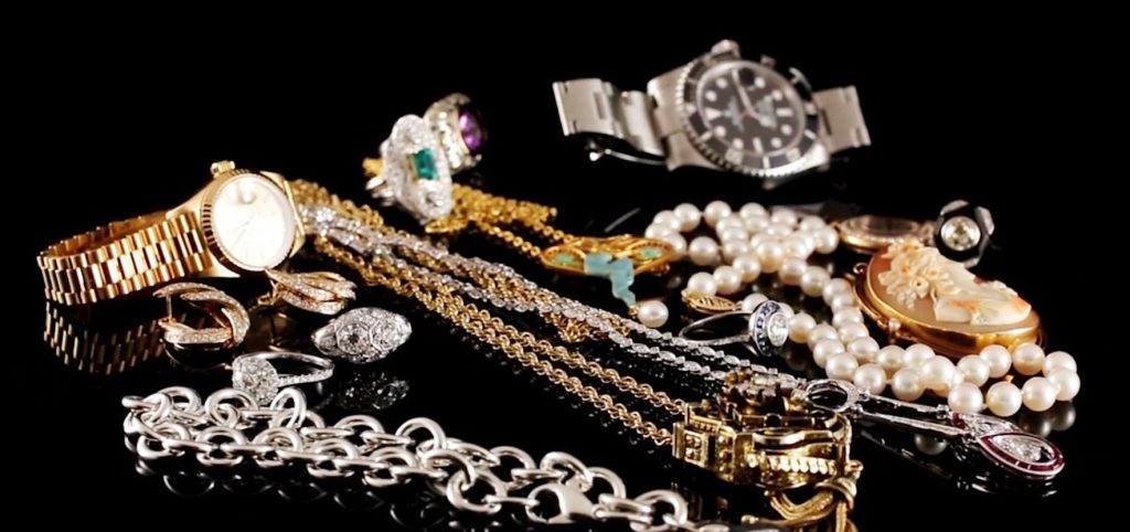 Various vintage and antique jewelry and accessories laid on a black table.