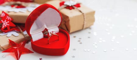 Rose gold diamond engagement ring in a heart-shaped red ring box.