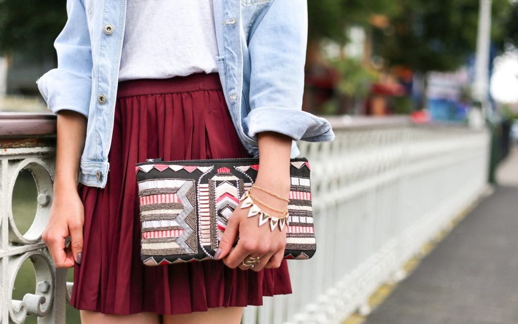 Woman wearing charm bracelet carrying small bag.