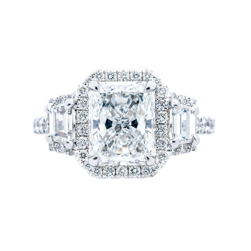 White gold three-stone diamond engagement ring with diamond haloes.