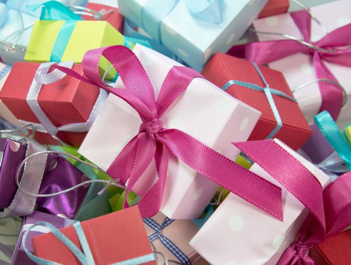 Stack of gift boxed wrapped in assorted neon paper and ribbons.