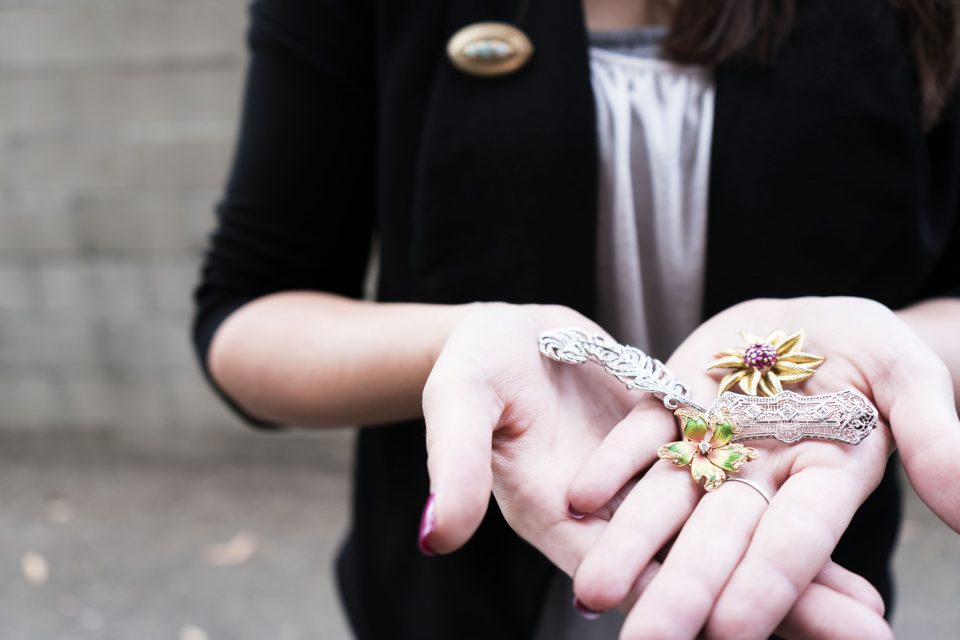 Woman holding out her palm face-up containing three brooches.