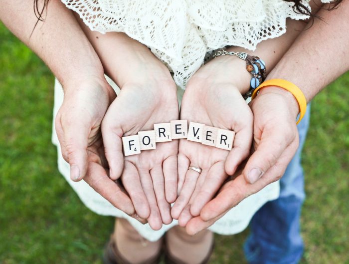 Open hands holding Scrabble letters spelling “Forever”.