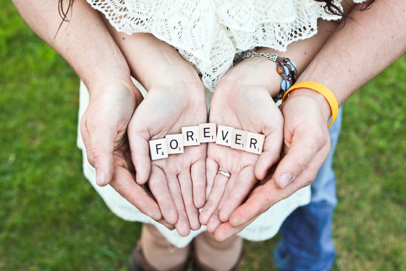 Open hands holding Scrabble letters spelling “Forever”.