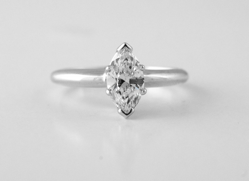 White gold solitaire engagement ring centered with a marquise cut diamond.