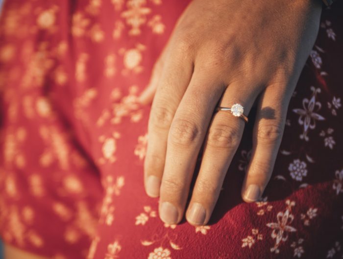 Woman’s hand featuring solitaire diamond engagement ring.