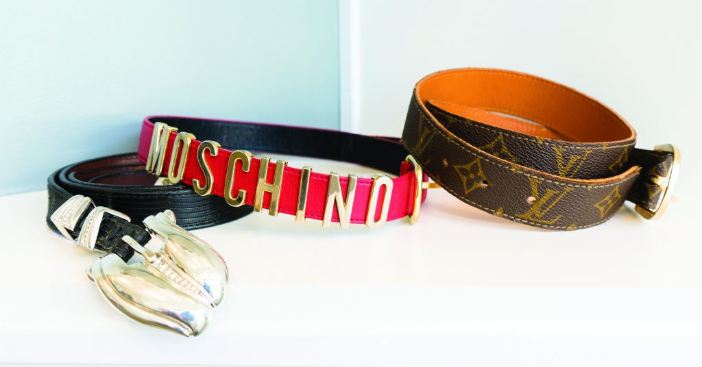 Three vintage designer belts on a white table.