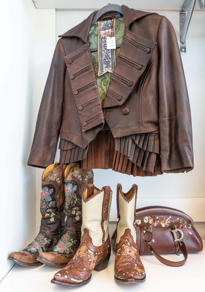 Western leather jacket, boots, and purse on display.