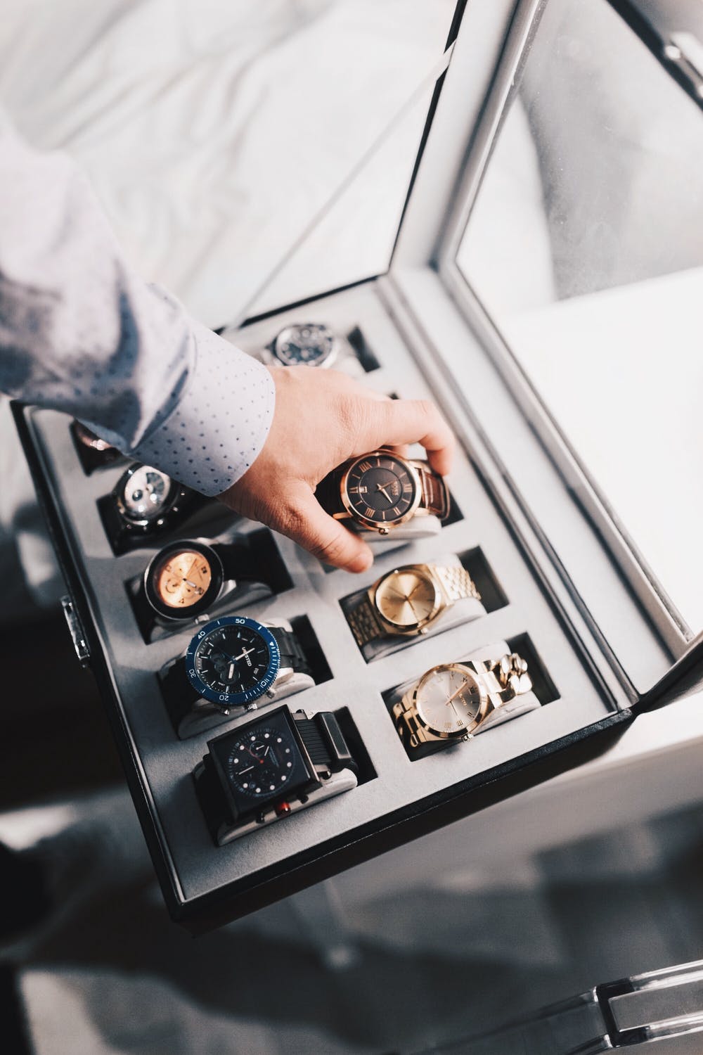 Man storing away a watch into a luxury watch box.