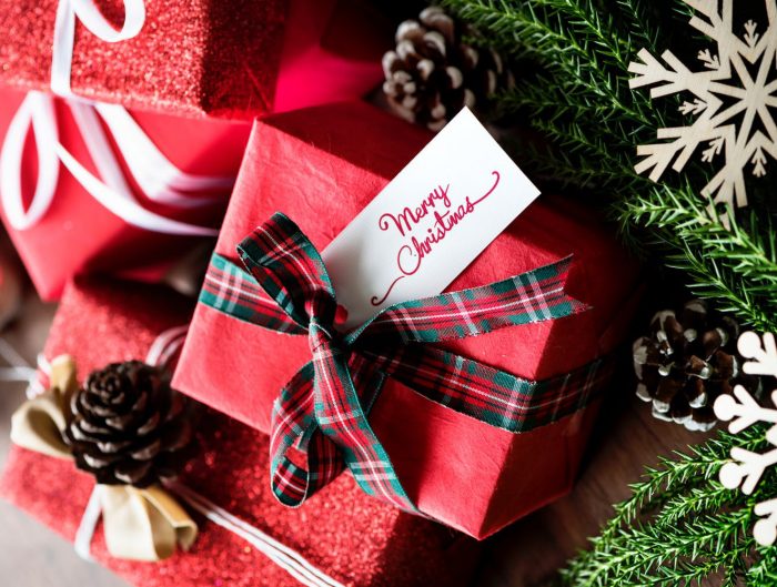 Gifts wrapped in red paper with Christmas ribbon and tag with text “Merry Christmas”.