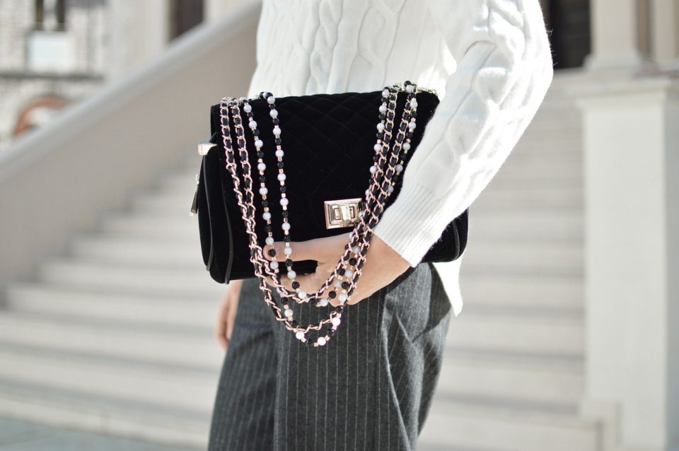 Large black handbag with beaded gold and leather chain strap.