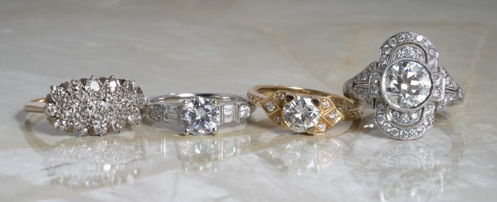 Four diamond engagement rings in various metals.