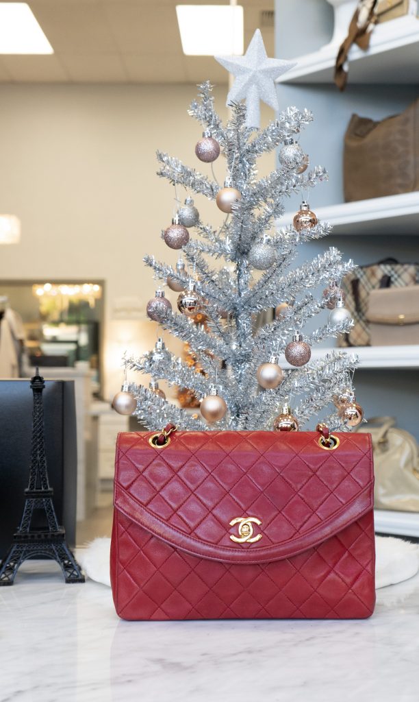 Vintage Chanel handbag on display in front of small white Christmas tree.