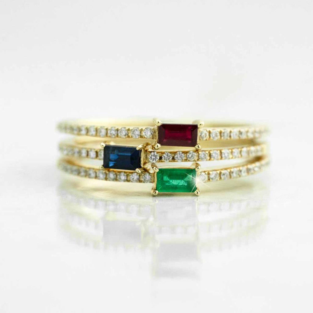 Yellow gold three-row ring set with diamonds, ruby, emerald, and blue sapphire.