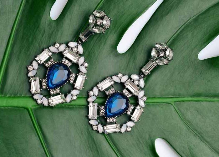 White gold drop earrings set with blue sapphires surrounded by diamonds.