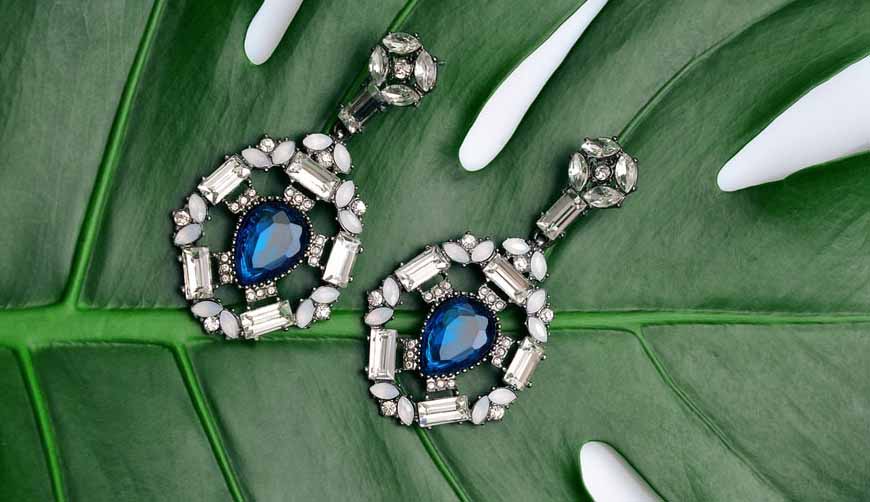 White gold drop earrings set with blue sapphires surrounded by diamonds.