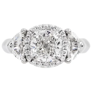 Platinum three-stone diamond engagement ring with a cushion-shaped diamond halo.