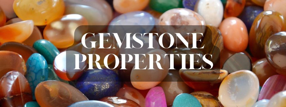 Pile of rough gemstones background with text “Gemstone Properties”.