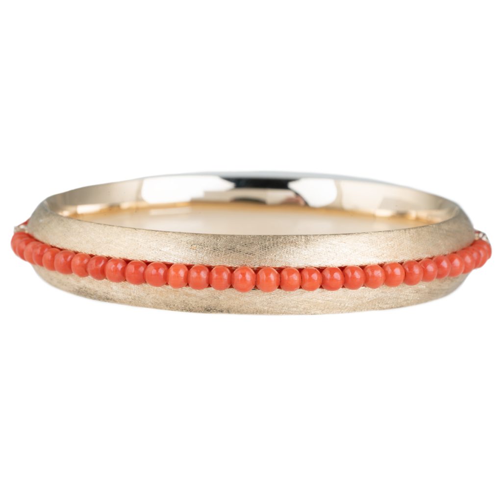 Yellow gold bangle set with coral beads.