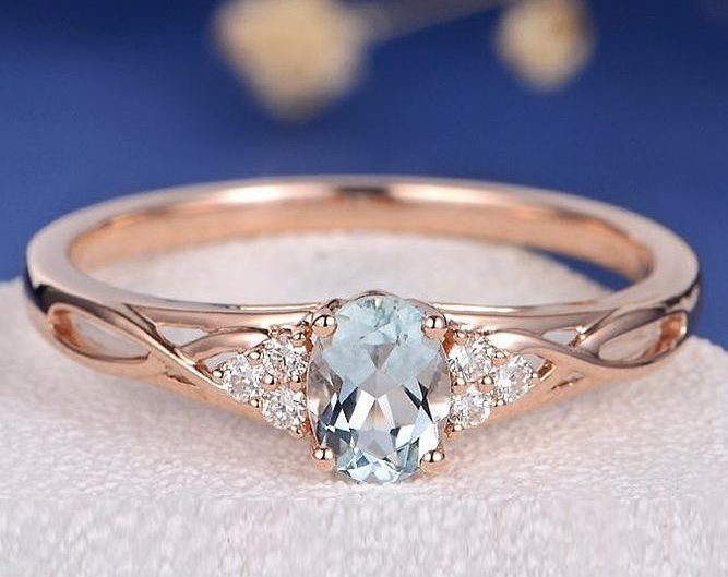 Yellow gold engagement ring centered with aquamarine and diamond sidestones.