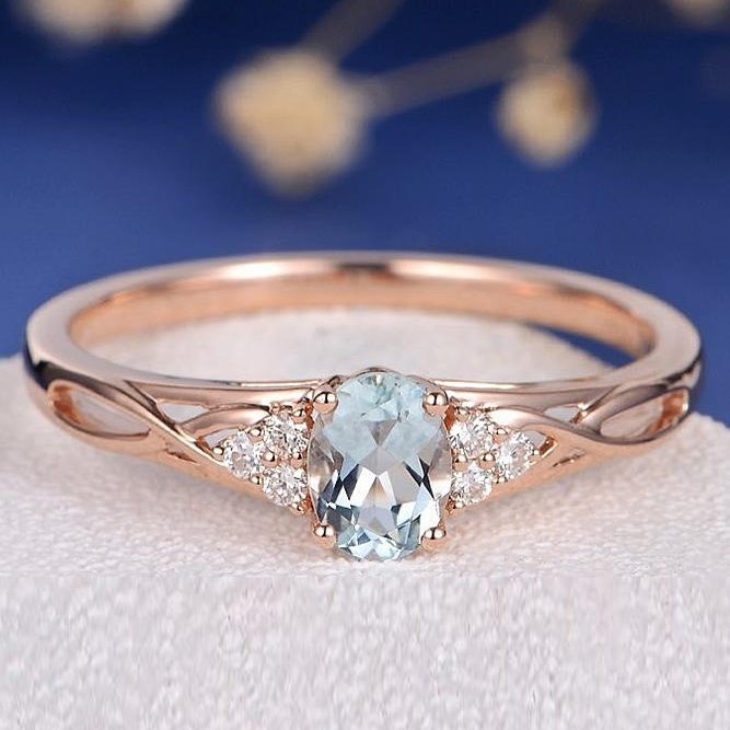 Yellow gold engagement ring centered with aquamarine and diamond sidestones.