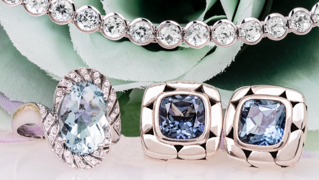 Group of aquamarine jewelry including a cocktail ring, tennis bracelet, and pair of earrings.