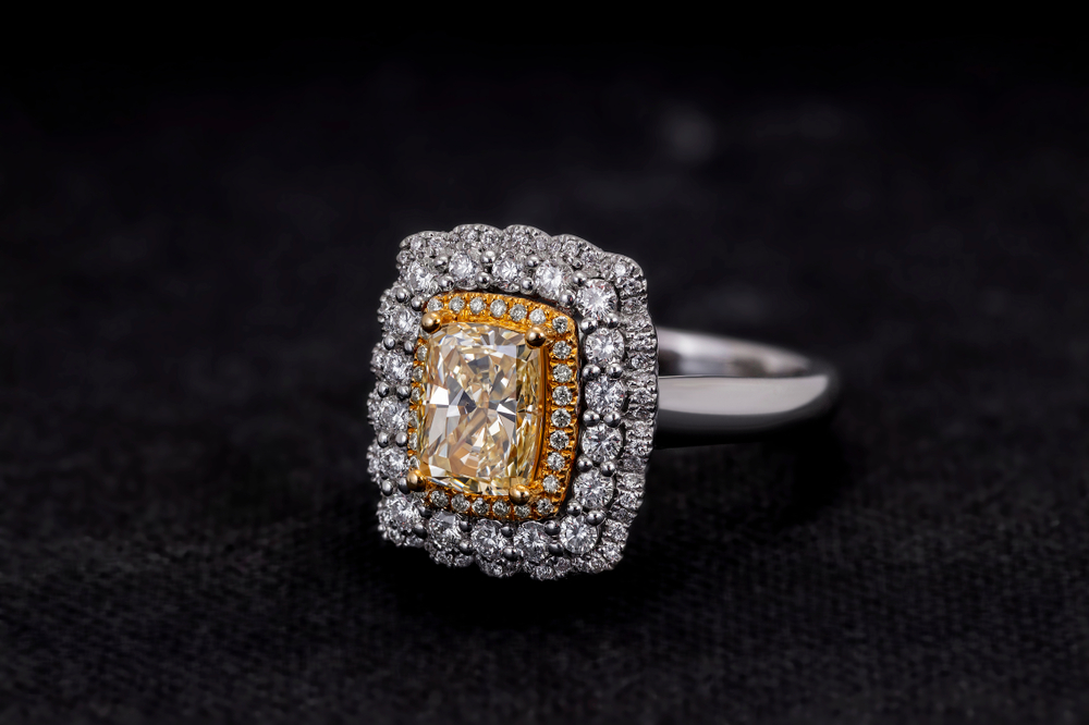 White gold engagement ring centered with a yellow diamond surrounded by round brilliant cut diamond double haloes.