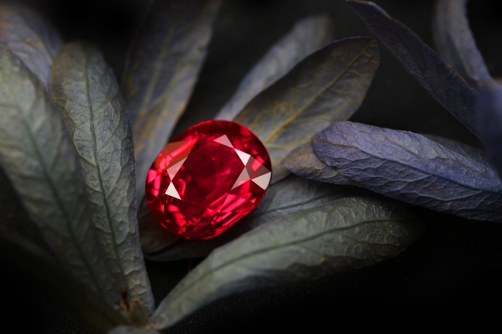 an oval cut ruby sitting on a leaf