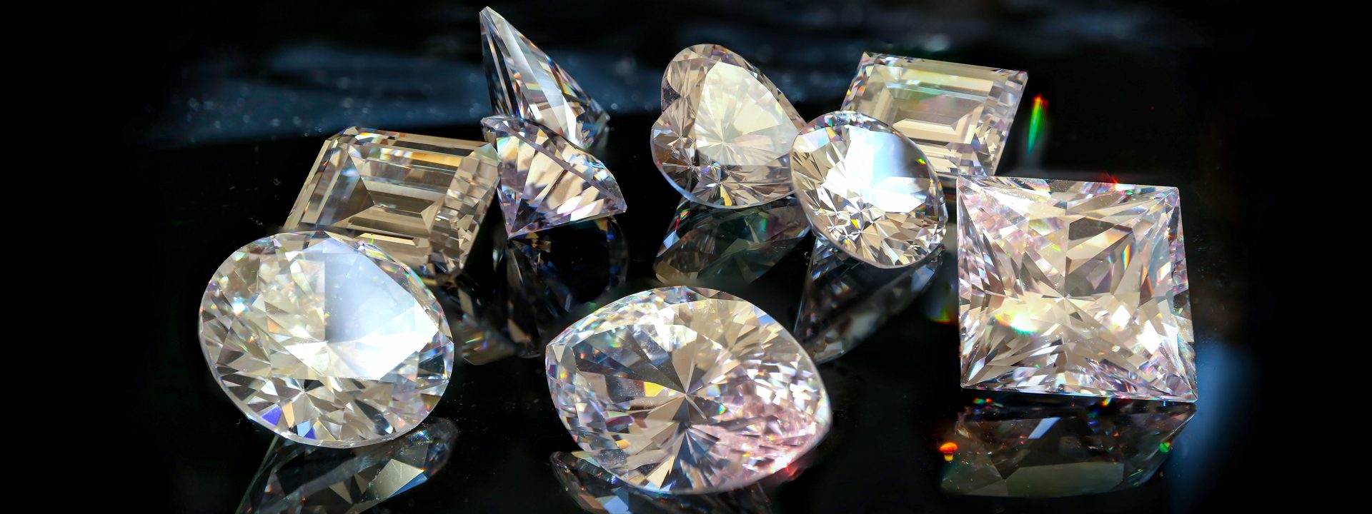 Several varied cuts of diamonds on a black table.