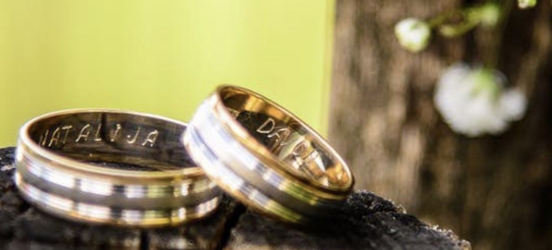 Two wedding bands set on a wooden log showcasing custom engraving.