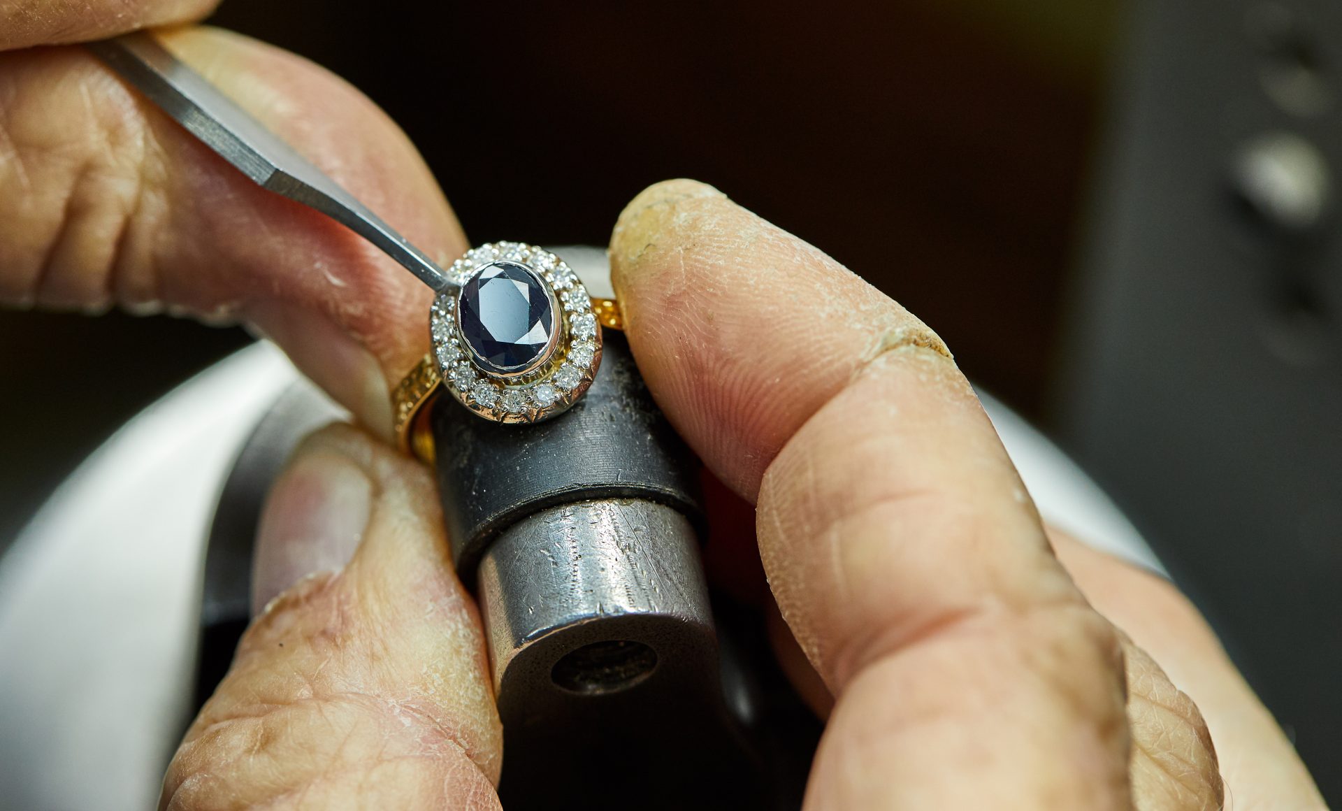 a jeweler setting a diamond in a sapphire halo ring 