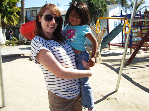 a woman holding a young child at a playground