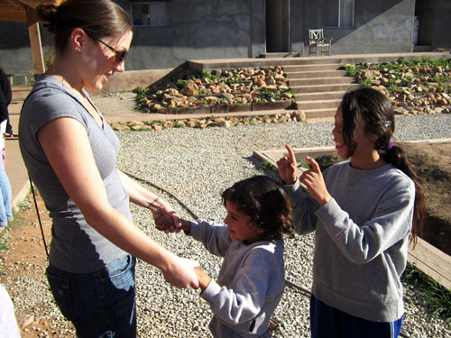 a woman greeting two children in a plaza 