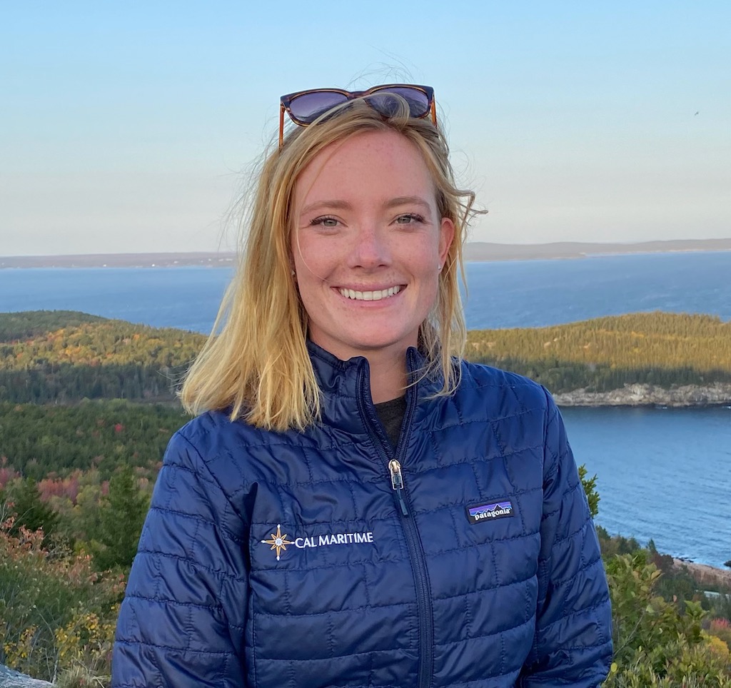 a smiling woman in front of a lake or bay