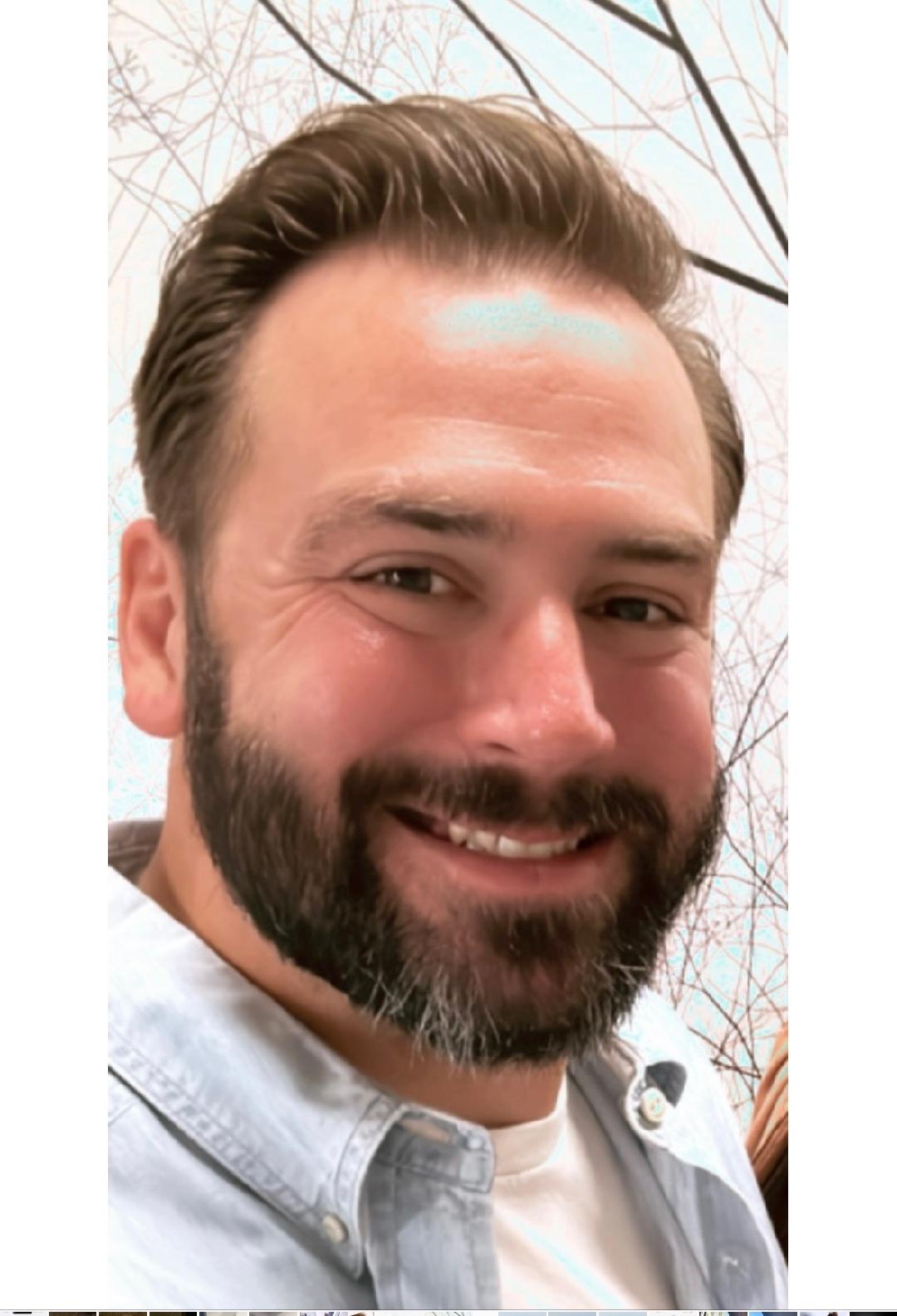 a bearded man smiling at the camera