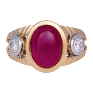 3-stone ring centered with a n oval cabochon ruby flanked by 2 diamonds, in a yellow gold setting