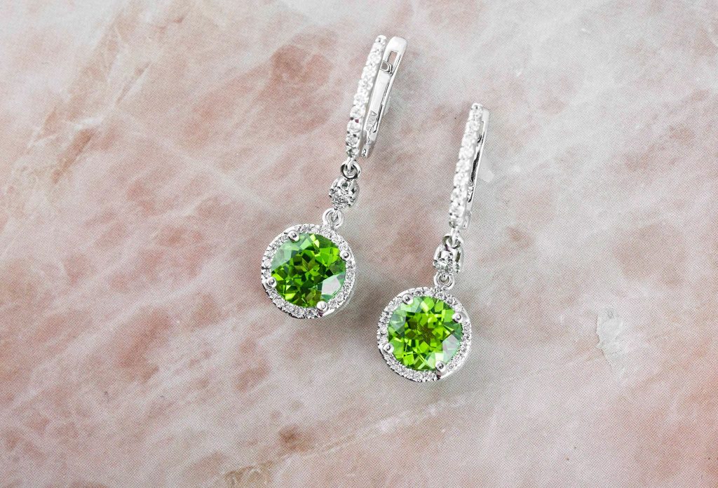 White gold drop earrings set with peridot and diamond haloes.