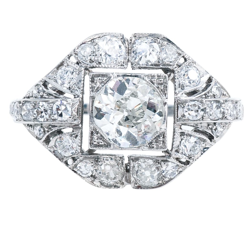 Art Deco diamond ring with a geometric design, featuring a brilliant-cut center stone surrounded by pavé diamonds in white gold.